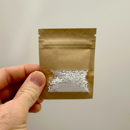 A hand holding a small packet of mineral concentrate for coffee brewing.